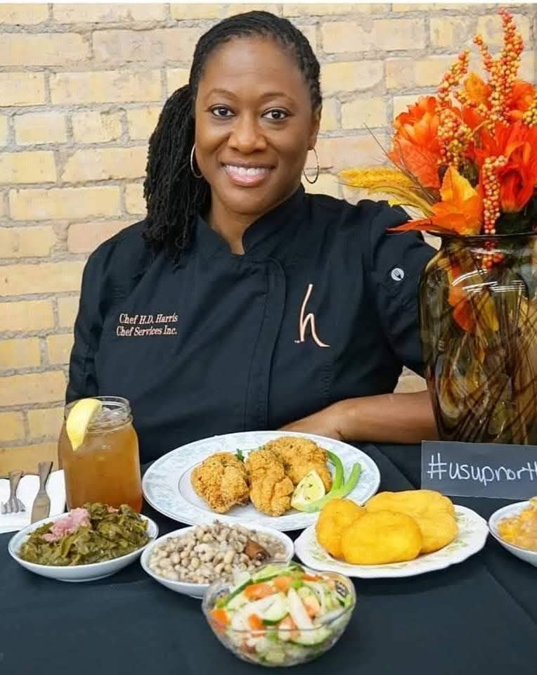 Chef Hardette Harris at a table of Southern dishes including fried fish